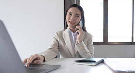 Young asian businesswoman beautiful charming smiling and talking on the mobile phone in the office.