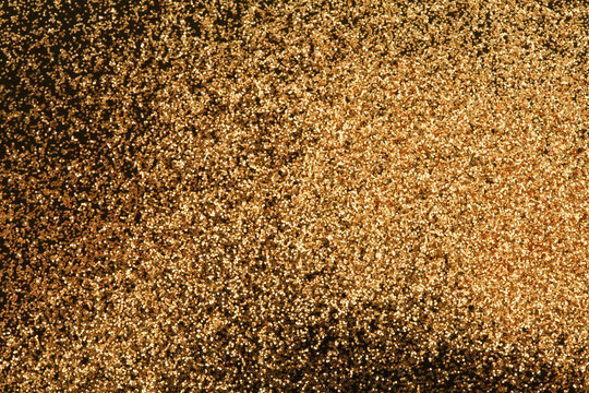 Gold and bronze glitter color confetti dots splash on black. Abstract glow shine background.