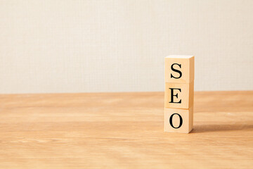 SEO。Search Engine Optimization。検索エンジン最適化。木製のブロックに描かれているSEOの文字。木製のテーブルの背景。