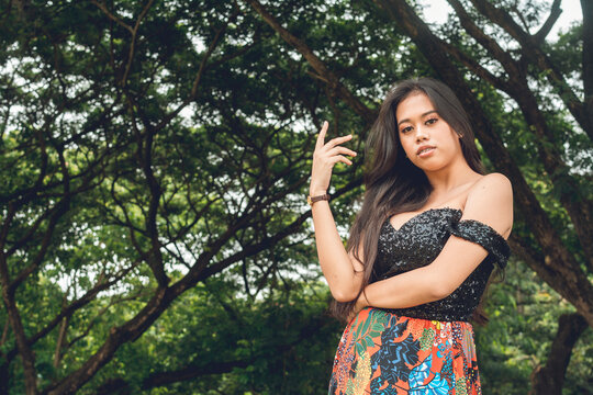 A voluptuous and curvy young Filipina woman posing at the park. A serious yet alluring look.