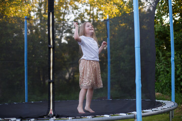 Little child girl jumping on the trampoline in the back yard