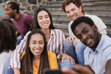 Obraz premium Happy multiracial friends taking a selfie using mobile phone in the city