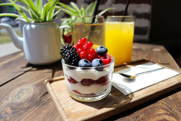 summer desserts with berries in a glass bowl and large glasses of homemade lemonade on a wooden  in a cafe