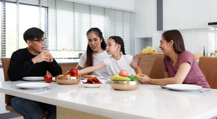 A large, happy Asian family spends their time dining at the tables inside the house. Little...
