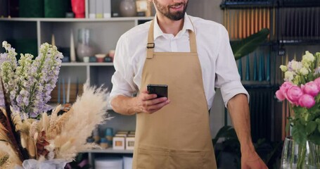 Caucasian male checks the flowers and enters data into the entire smartphone entrepreneur texting in flower shop