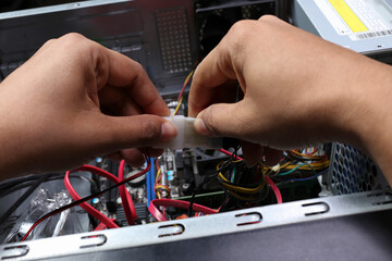 Close-up shot of a technician's hands connecting internal computer cables