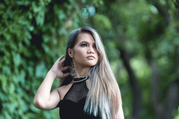 An emo and goth asian lady with blonde dyed hair in a sexy black dress. Outdoor shoot.