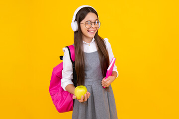 Back to school. School child, teenage student girl with bagpack hold apple and book isolated on yellow. Happy face, positive and smiling emotions of teenager girl.