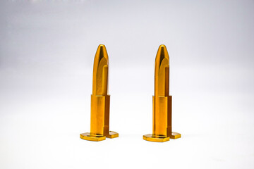 The dark gold cylindrical bar has a circular base perforated with curved grooves. The pointed end is placed on a white background.