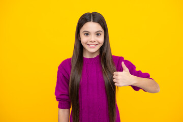 Like it. Portrait of joyful teenage child girl showing thumbs up and smiling, yellow background with copy space.