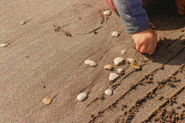 manos jugando con caracoles en la arena. niña jugando en la playa