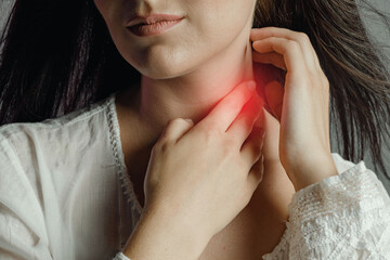 Woman touches neck throat with hand, tonsillitis and sore throat