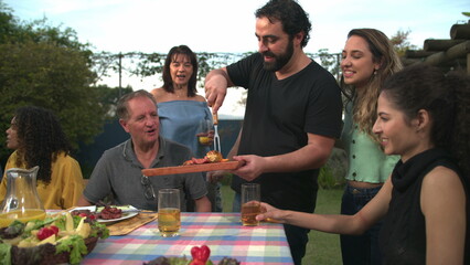 Son serving father food during backyard barbecue during summer day
