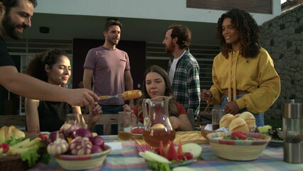 Friends having barbecue. BBQ Chef bringing corn. People gathered outside at home backyard