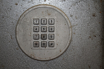 Old payphone dial with square buttons.
