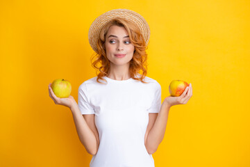 Happy young girl holding apple isolated over yellow background. Portrait of pretty woman with an apple close up.