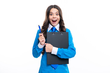 Funny teenager girl in shirt and tie wearing office uniform holding clipboard on white isolated background. Excited face. Amazed expression, cheerful and glad.