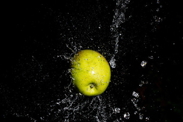 Red apple thrown through a water curtain with splash