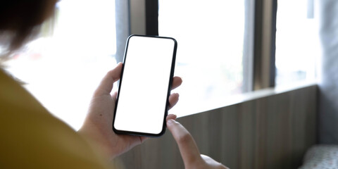 Young Asian woman using smartphone (white screen) at coffee shop. technology and bussiness concept background.