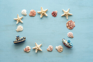 Starfishes, seashells, decorative boats laid out in the frame on blue wooden background.