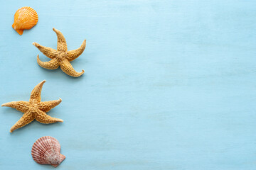 Starfishes and seashells on blue wooden background with copy space.
