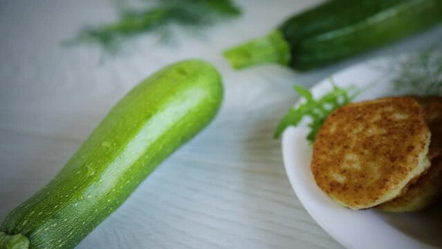 fried vegetable pancakes from squash and zucchini with herbs, on a light wooden table.