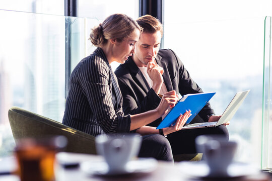 Two young business man and woman talking with each other by looking at the discussion board.
