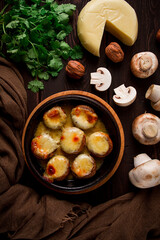 Traditional Georgian dish, appetizer, stuffed mushrooms, Sulguni cheese, baked in a Ketzi clay pan, on a wooden table, close-up, no people,