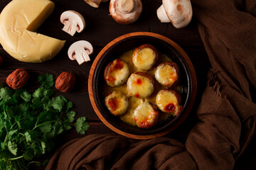 Traditional Georgian dish, appetizer, stuffed mushrooms, Sulguni cheese, baked in a Ketzi clay pan, on a wooden table, close-up, no people,