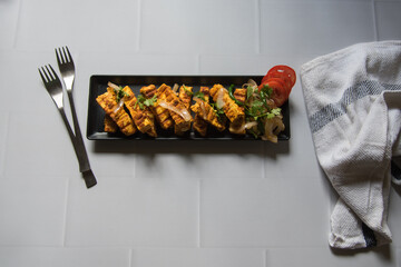 Tandoori grilled paneer or cottage cheese cubes with veggies in a tray. Top view, selective focus. 