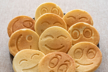 Pancakes in the form of funny faces for kid's breakfast on cotton fabric background.