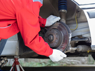 Male mechanic wearing uniform examining car suspension and axle bearing. Prevention of car suspension and accidents on the road