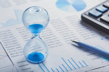 Best time for investment. Hourglass, financial charts and calculator.