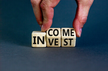Invest or income symbol. Concept words Invest and Income on wooden cubes. Businessman hand. Beautiful grey table grey background. Business and invest or income concept. Copy space.