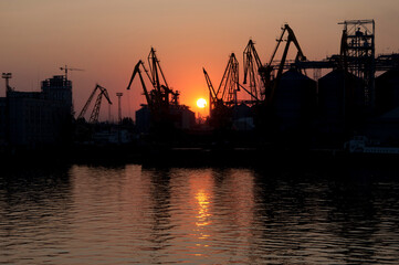 Odesa sea port gantry crane silhouettes at sundown sky background