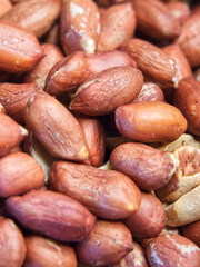 Roasted unpeeled peanuts macro, peanuts as a background. A lot of peeled peanuts. Full frame with peanuts. Selective focus.