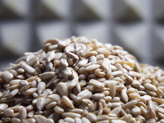 A pile of peeled sunflower seeds on a wooden surface, macro shot. Sunflower seeds without shell.