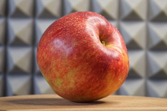 A single large ripe apple on a wooden surface, side view. Fruit macro.