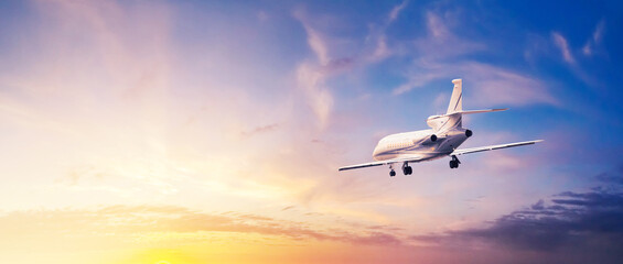 Modern corporate business jet during flight against the background of the sunset sky. Horizontal...