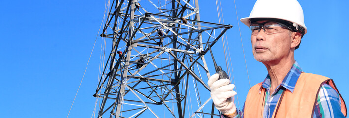 electrical engineer near transmission line An electrician manages the process of building a transmission line. Engineers wear helmets and reflectors and radio transmitters at work.