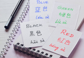 Learning Chinese Language with different colors name. Handwritten flash cards in English and Chinese languages ​​and their translations. Selective focus on the text.