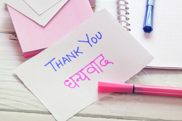 Thank you Dhanyavaad (Hindi translation) handwritten text on study table. Close up image, selective...
