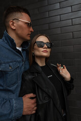 Fashionable trendy beautiful couple woman and man in fashion outfit with trendy sunglasses in black...