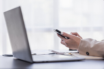 Asian businesswoman using mobile phone indoor, Asian businesswoman working on laptop in modern office.