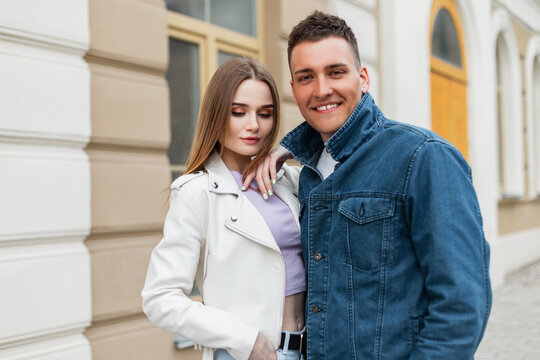Happy beautiful fashionable young couple pretty woman and handsome man in fashionable denim casual clothes stands on the street