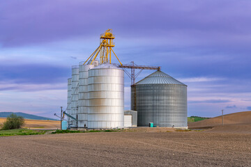 Agricultural scene of grain bins and silos under a colorful sky at sunset in the Palouse Hills, Washington, USA © Jim Ekstrand