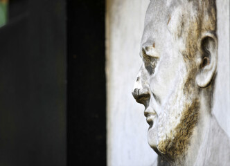 Side view on an old, weathered sandstone relief that shows the face of an elder man. 