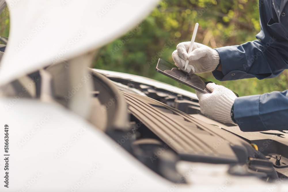 Aufkleber close-up of man in uniform working on digital tablet while standing in front of car hood in workshop