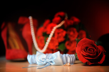 Bright red shoes and a bright red bouquet on a dark background How to see a pearl necklace. High quality photo