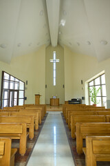 Interior of modern Catholic church with two rows of wooden benches for parishioners and long aisle...